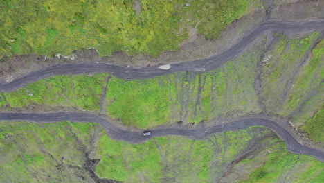 Downward-angle-drone-shot-following-a-vehicle-driving-on-the-Road-to-Tusheti,-one-of-the-worlds-most-dangerous-roads