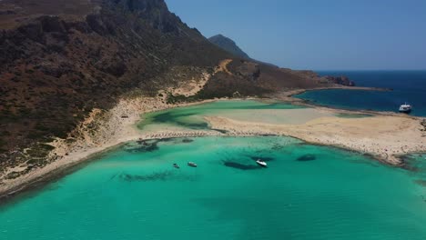 Aerial-descending-over-Balos-Beach-and-Lagoon-with-turquoise-water,-mountains-and-cliffs-in-Crete,-Greece