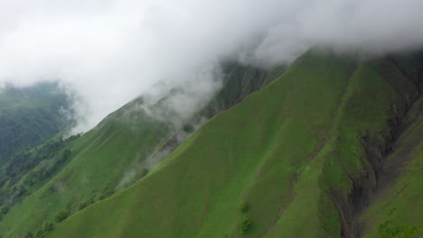 Drone-shot-of-clouds-coming-down-a-mountain-cliff-in-the-Caucasus-Mountains-in-Georgia