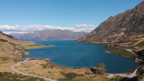 Luftdrohnenaufnahme-Eines-Blauen-Majestätischen-Sees-Umgeben-Von-Bergen-In-Neuseeland-An-Einem-Sonnigen-Sommertag-In-4k