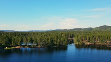 Aerial-View-Of-Peaceful-Lake-With-Clear-Blue-Sky-And-Lush-Vegetation---Busjon-Lake,-Appelbo,-Dalarna,-Sweden---drone-shot
