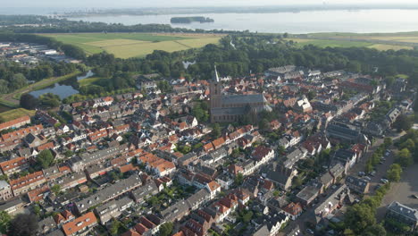 Flying-away-from-beautiful-large-church-in-the-beautifully-preserved-fortress-town-Naarden,-the-Netherlands-and-revealing-the-entire-city