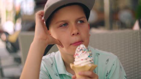 Portrait-of-blond-caucasian-boy-eating-and-enjoying-creamy-cold-ice-cream-in-a-waffle-cone