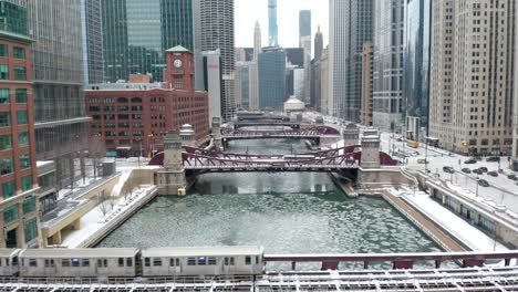 Amazing-Aerial-Establishing-Shot,-Subway-Train-Over-Frozen-Chicago-River,-Winter