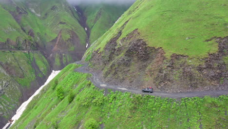 Cinematic-drone-shot-of-a-vehicle-driving-on-the-Road-to-Tusheti,-one-of-the-worlds-most-dangerous-roads