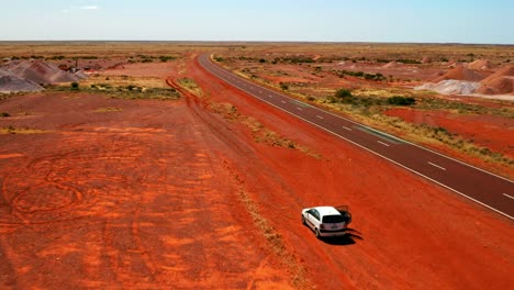 Zoom-in-Aerial-View-of-a-car-on-a-roadside-of-Stuart-Highway-in-Midday,-NT---Australia