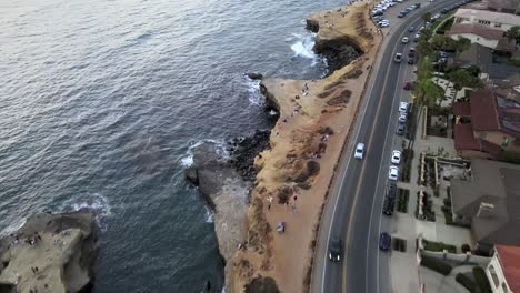 Aerial-of-Sunset-Cliffs,-waves-roll-towards-coastal-shore,-San-Diego