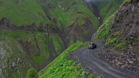 Dramatic-drone-shot-of-a-vehicle-driving-on-the-Road-to-Tusheti,-one-of-the-worlds-most-dangerous-roads