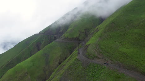Rotating-drone-shot-of-vehicle-driving-on-the-the-Road-to-Tusheti,-one-of-the-worlds-most-dangerous-roads-in-Georgia