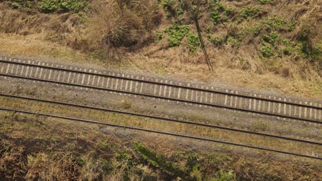 Aerial-top-down-of-railroad-tracks-in-rural-area-during-sunny-day---ascend-drone