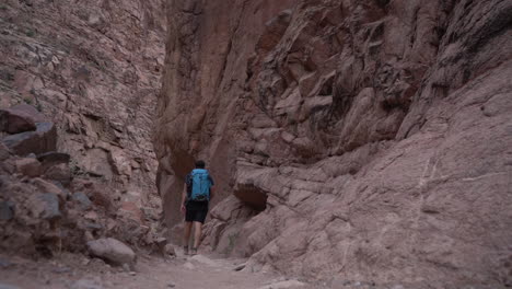 Lonely-Male-Hiker-With-Backpack-Walking-Into-Narrow-Slot-Canyon-in-Grand-Canyon-National-Park,-Bright-Angel-Hiking-Trail,-Arizona-USA,-Full-Frame-Slow-Motion