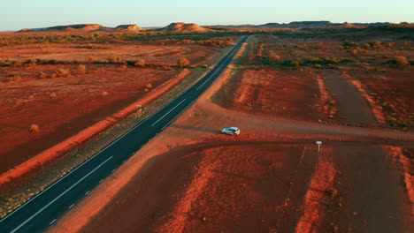 Coche-Blanco-Estacionado-En-El-Desierto-De-Color-Rojo-Cerca-De-La-Carretera-Asfaltada-En-Alice-Springs,-Australia