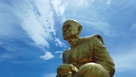 Riesige-Goldene-Statue-Des-Mönchs-Luang-Pu-Thuat,-Der-Schüler-Von-Lord-Buddha-In-Seiner-Meditationsposition-Vor-Blauem-Himmel-Und-Cirrocumulus-wolkenhintergrund-In-Phuttha-Utthayan-Maharat-Ayutthaya-Thailand
