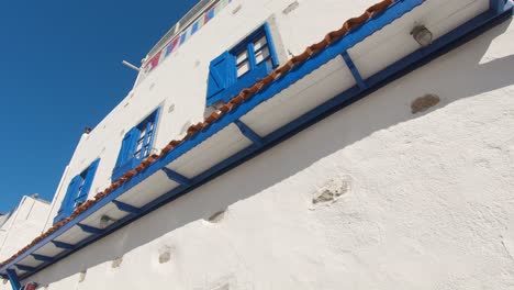 Low-angle-shot-of-popular-aegean-style-building,-white-facade-and-blue-window-frame,-summer-vibe