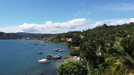 Aerial-view-of-tropical-beach,-bay-with-boats-and-mountain-scenery,-Samana-Peninsula,-Dominican-Republic