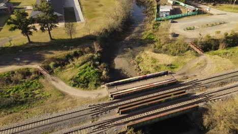 AERIAL---Person-jogging-next-to-railway-and-river-in-Maschwitz,-Argentina