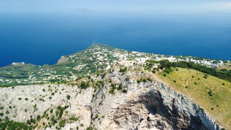 Drone-flight-along-top-of-Mount-Solaro,-tilt-down-shot-of-rugged-cliffs,-Capri,-Italy