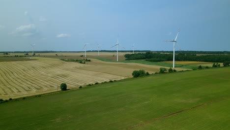 Energy-producing-wind-turbines-in-green-fields-of-Zwartowo-Pomerania,-Poland,-aerial-panning-shot
