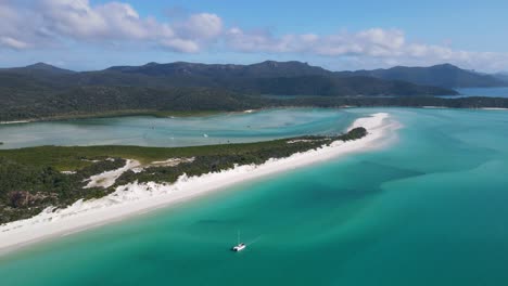 Sailboat-Floating-Off-The-Shore-Of-Whitehaven-Beach-With-Whitest-Silica-Sand-And-Dense-Vegetation-In-Whitsundays,-North-Queensland,-Australia