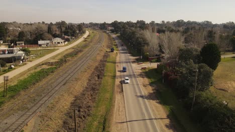 Aerial-shot-of-cars-driving-on-rural-road-in-suburb-area-of-Buenos-Aires-during-summertime---Tilt-down-4K-shot