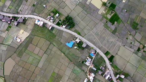Aufnahme-Von-Oben-Nach-Unten-Von-überfluteten-Reisfeldern-Auf-Dem-Land-Mit-Straße,-Die-Von-Der-Mitte-Führt