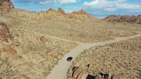 Aerial-View-of-Dark-Van-Vehicle-Moving-on-Desert-Road-in-Dry-Landscape-on-Sunny-Day