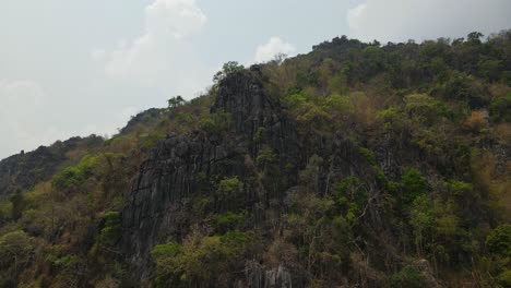 4K-Aerial-dolly-in,-spectacular-view-of-limestone-rock-formation-on-the-cliffside-on-rugged-terrain-in-the-mountains-during-a-summer-season-in-Thailand-Southeast-Asia