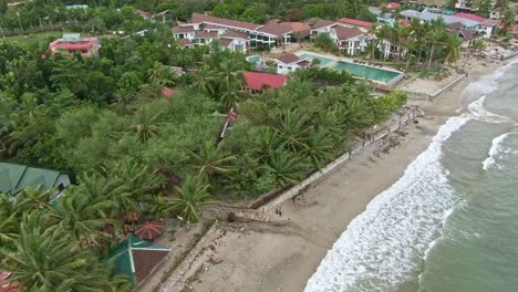 Aerial-relaxing-shot-of-beach,-sandy-sand-and-landscape-of-structure-of-seaside-view-in-Puerto-Galera,-Philippines
