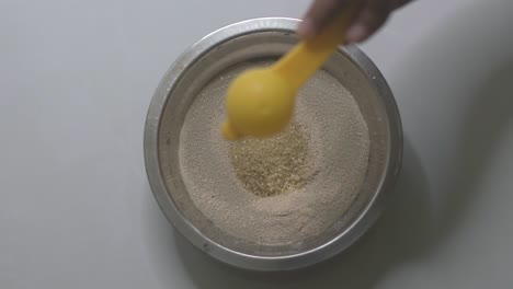 Adding-one-teaspoon-of-sugar-to-the-yeast-and-warm-water-mixture-in-a-small-bowl