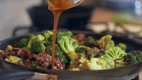 Adding-the-sauce-to-the-beef-and-broccoli-stir-fry-meal---slow-motion