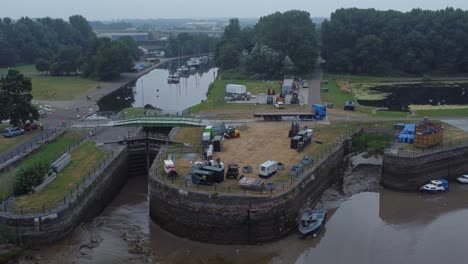 Aerial-view-Spike-island-council-workers-removing-Resurrection-concert-barriers-from-river-canal-park-orbit-slow-right