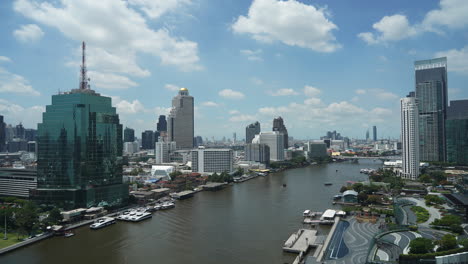 Day-Time-lapses-Water-traffic-and-boat-traffic-in-Chao-Praya-River-surrounded-with-fancy-luxury-hotels-and-skyscrapers,-Bangkok-Thailand