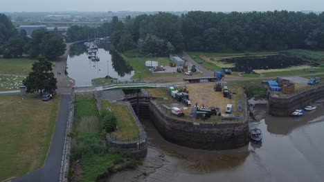 Aerial-view-Spike-island-council-workers-removing-Resurrection-concert-barriers-from-river-canal-park-low-orbit-right