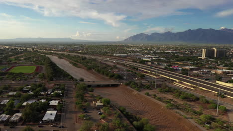 Aerial-View-Of-Santa-Cruz-River-And-Road-Bridge-In-Tucson,-Arizona-With-Catalina-Mountains-In-Distance