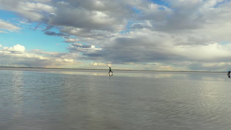 Man-Running-on-Salt-Flats-With-Sky-Reflection-on-Water-and-Endless-Horizon
