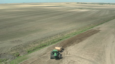 Panorama-De-Un-Tractor-Cargado-Con-Tierra-Conduciendo-En-El-Vasto-Paisaje-En-Saskatchewan,-Canadá