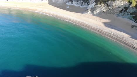 Aerial-Dolly-Back-Reveal-Of-Durdle-Door-Surrounded-By-Calm-Turquoise-Waters