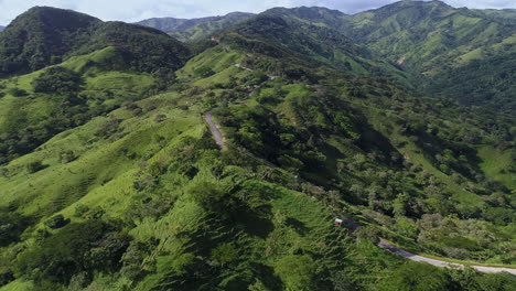 Empujando-Una-Toma-Aérea-Siguiendo-Una-Ventosa-Carretera-Rural-De-Montaña-Hasta-Una-Exuberante-Cordillera,-4k