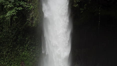 Slow-motion-shot-following-water-down-rain-forest-waterfall-into-pool-below