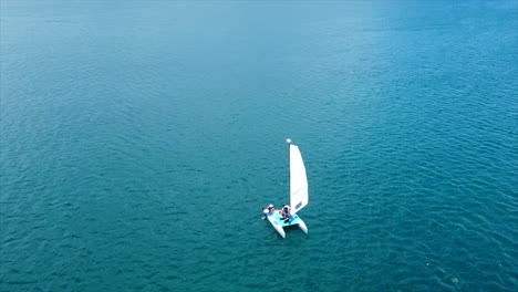 Eine-Luftaufnahme-Eines-Kleinen-Segelboots-Im-Blau-Der-Karibischen-Gewässer-An-Einem-Sonnigen-Tag