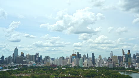 Time-lapse-of-Fantastic-fast-Clouds-moving-over-the-modern-Bangkok-cityscape,-Benjakitti-Park-and-Lake-in-front-daytime