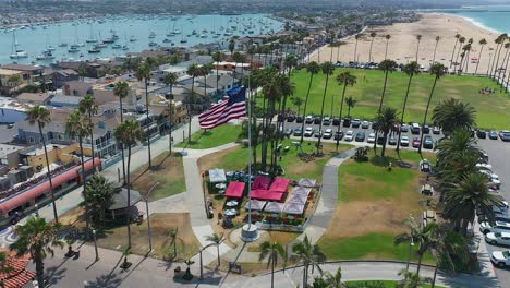 Aerial-view-of-an-American-flag-blowing-in-the-wind-at-Peninsula-Park,-in-Newport-Beach,-California