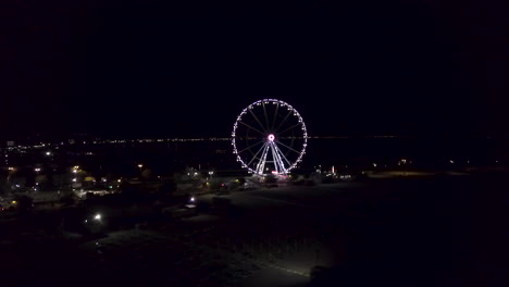 Illuminated-Ferris-Wheel-Against-Sky-At-Night-In-Rimini,-Italy---aerial-shot