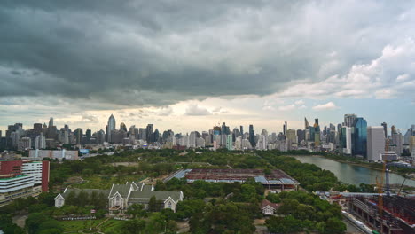 Heavy-Rain-Clouds-Forming-Over-City-center-Benjakitti-Park-and-Lake-,-Cloudscape-Skyline-in-Bangkok-Thailand-on-sunset,-Queen-Sirikit-National-Convention-Centre-construction-site-time-lapse