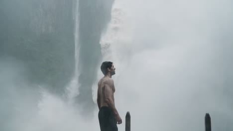 Elated-man-celebrates-in-front-of-massive-Bajos-del-Toro-waterfall-in-monsoon-rain