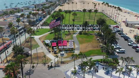 Pull-away-aerial-view-of-an-American-flag-at-Peninsula-Park,-in-Newport-Beach,-California