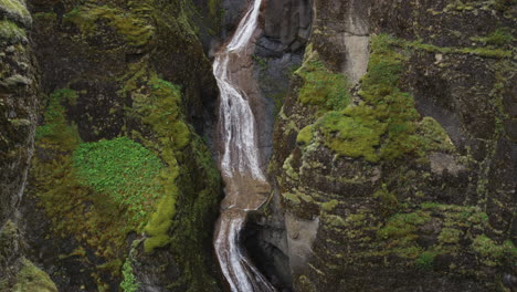Super-smooth-tilt-down-view-of-waterfalls-running-into-the-canyons-of-Fjadrargliufur-in-Iceland's-dramatic-wilderness-landscape