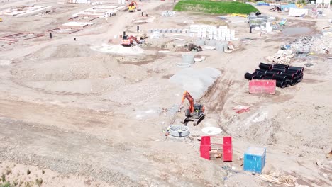 Excavation-digger-vehicle-preparing-cement-pipe-aerial-view-on-housing-development-construction-site
