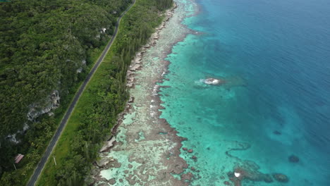 Aerial-view-of-a-coral-reefs-and-clear-blue-waters-on-the-coast-of-the-Loyalty-islands---reverse,-drone-shot