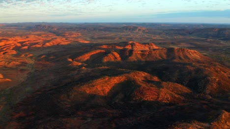 Puesta-De-Sol-Roja-Brillante-Sobre-El-Paisaje-Montañoso-De-Alice-Springs,-Australia--antena